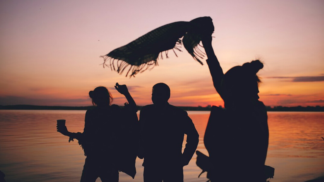 Small team of Croatian tech colleagues celebrating outdoors with raised hands